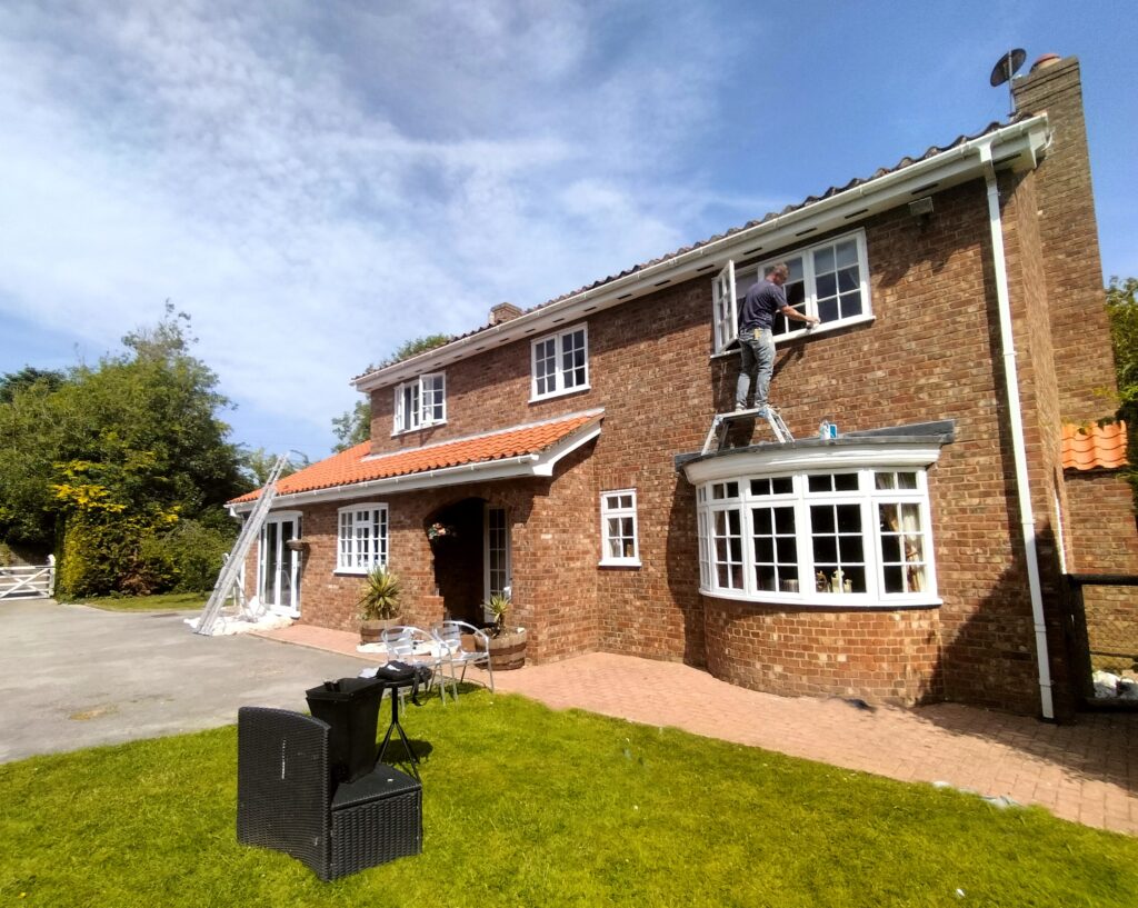 Exterior painting work in York on a brick house with white window frames and tiled roof